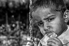 인상을 쓰며 그네를 타고 빵을 먹고있는 꾀죄죄한 남자아이